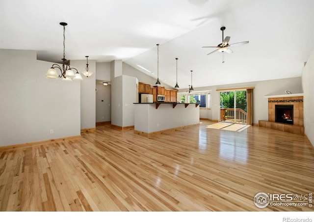333 Braveheart Ln, Johnstown, CO 80534 - unfurnished living room with lofted ceiling, light wood finished floors, ceiling fan, a tiled fireplace, and a chandelier