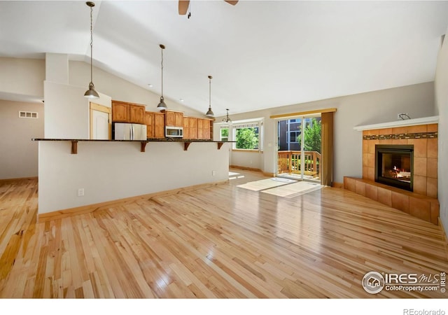 333 Braveheart Ln, Johnstown, CO 80534 - unfurnished living room featuring vaulted ceiling, light wood-type flooring, a tile fireplace, and a ceiling fan