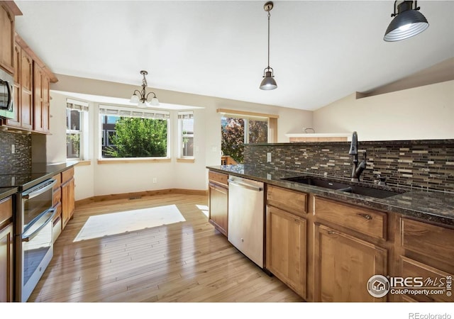 333 Braveheart Ln, Johnstown, CO 80534 - kitchen with stainless steel appliances, decorative backsplash, light wood-style floors, decorative light fixtures, and a chandelier