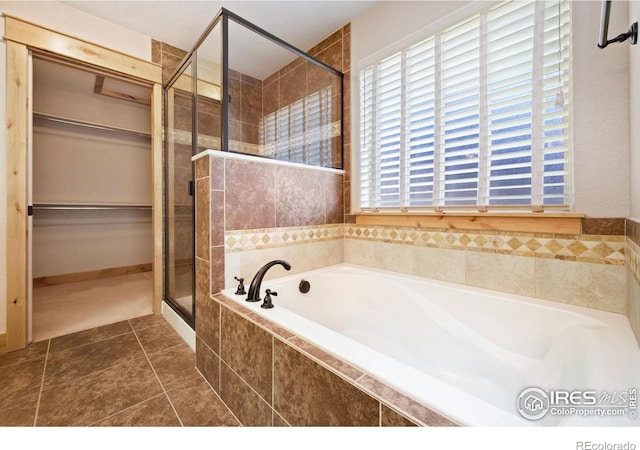 333 Braveheart Ln, Johnstown, CO 80534 - bathroom with a garden tub, a shower stall, a walk in closet, and tile patterned floors