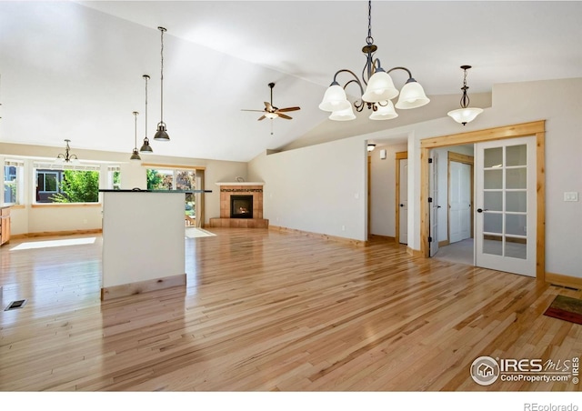 333 Braveheart Ln, Johnstown, CO 80534 - unfurnished living room with light wood-style floors, vaulted ceiling, a chandelier, a tiled fireplace, and french doors