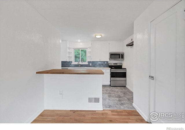 6755 W 33rd Ave, Wheat Ridge, CO 80033 - kitchen featuring appliances with stainless steel finishes, wooden counters, white cabinetry, tasteful backsplash, and open shelves