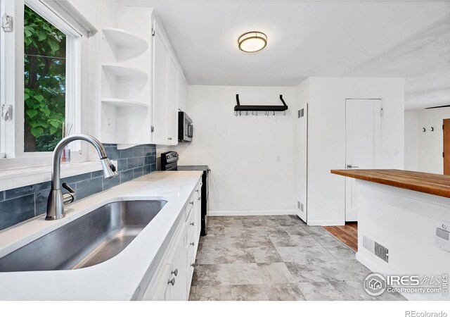 6755 W 33rd Ave, Wheat Ridge, CO 80033 - kitchen featuring open shelves, black electric range, stainless steel microwave, white cabinets, and decorative backsplash