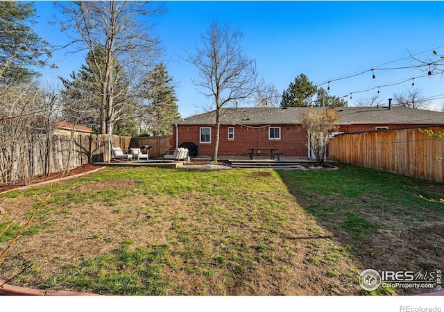 6755 W 33rd Ave, Wheat Ridge, CO 80033 - back of property featuring a fenced backyard, a patio area, a wooden deck, and brick siding