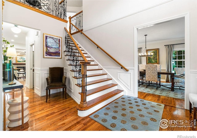 3000 E Cedar Ave Unit 2, Denver, CO 80209 - stairs featuring wood finished floors, ornamental molding, a decorative wall, a chandelier, and a fireplace