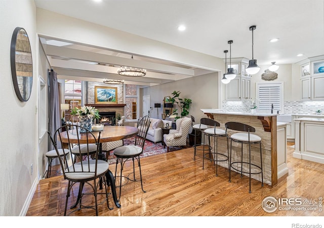 3000 E Cedar Ave Unit 2, Denver, CO 80209 - dining space featuring a lit fireplace, light wood-type flooring, and recessed lighting