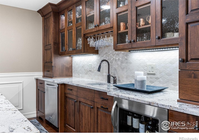 3000 E Cedar Ave Unit 2, Denver, CO 80209 - kitchen featuring decorative backsplash, light stone counters, glass insert cabinets, dark brown cabinetry, and wainscoting