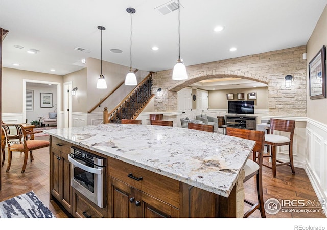 3000 E Cedar Ave Unit 2, Denver, CO 80209 - kitchen featuring a decorative wall, arched walkways, wainscoting, dark wood finished floors, and oven