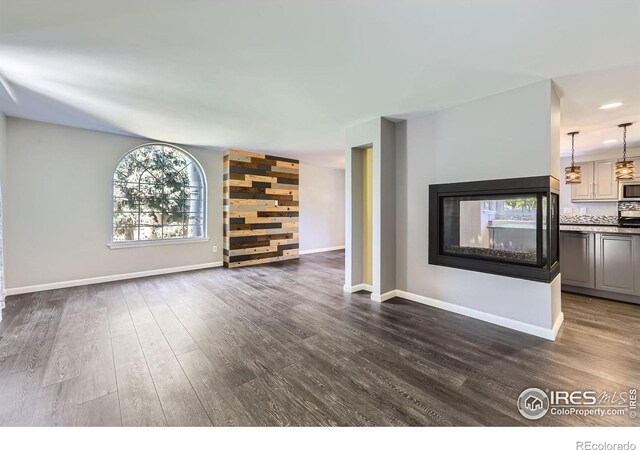 5491 E 117th Ave, Thornton, CO 80233 - unfurnished living room with dark wood finished floors and a multi sided fireplace
