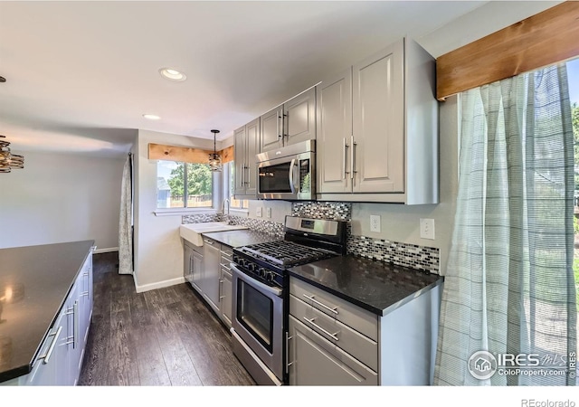 5491 E 117th Ave, Thornton, CO 80233 - kitchen with appliances with stainless steel finishes, dark countertops, dark wood-type flooring, decorative backsplash, and recessed lighting