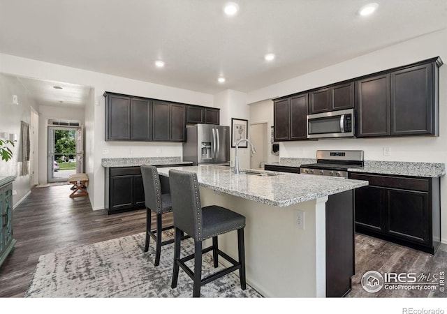1781 Summer Bloom Dr, Windsor, CO 80550 - kitchen with appliances with stainless steel finishes, dark wood finished floors, recessed lighting, an island with sink, and a kitchen breakfast bar