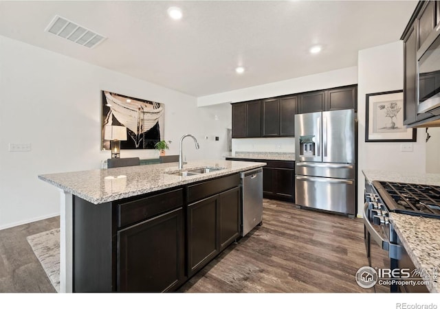 1781 Summer Bloom Dr, Windsor, CO 80550 - kitchen featuring stainless steel appliances, dark wood-style flooring, a kitchen island with sink, light stone counters, and recessed lighting