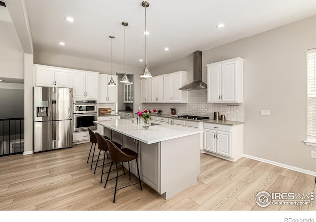 1389 Lyons Ln, Erie, CO 80516 - kitchen with stainless steel appliances, wall chimney range hood, light wood finished floors, tasteful backsplash, and recessed lighting