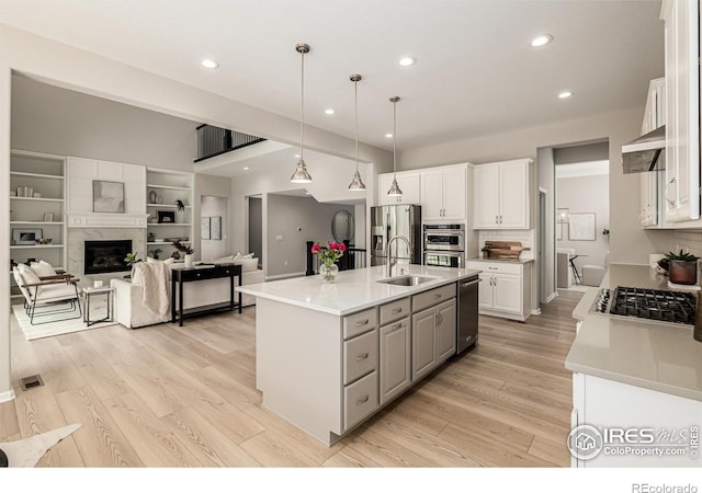 1389 Lyons Ln, Erie, CO 80516 - kitchen with white cabinetry, stainless steel appliances, light wood-style flooring, recessed lighting, and light countertops