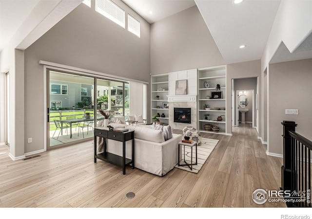 1389 Lyons Ln, Erie, CO 80516 - living area with plenty of natural light, light wood-style flooring, a towering ceiling, a tiled fireplace, and recessed lighting