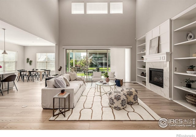 1389 Lyons Ln, Erie, CO 80516 - living room featuring a towering ceiling, wood finished floors, a premium fireplace, healthy amount of natural light, and built in features
