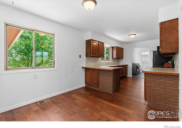 3400 Erving Ct, Berthoud, CO 80513 - kitchen featuring independent washer and dryer, dark wood-type flooring, light countertops, a peninsula, and a textured ceiling