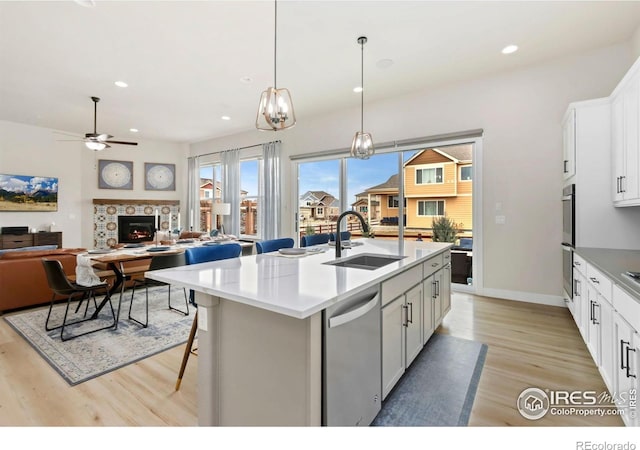 2156 Setting Sun Dr, Windsor, CO 80550 - kitchen featuring appliances with stainless steel finishes, light wood finished floors, ceiling fan, recessed lighting, and white cabinetry