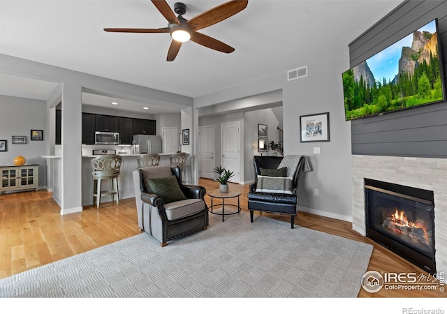 6042 Carmon Dr, Windsor, CO 80550 - living area featuring a ceiling fan, a glass covered fireplace, and light wood-style flooring