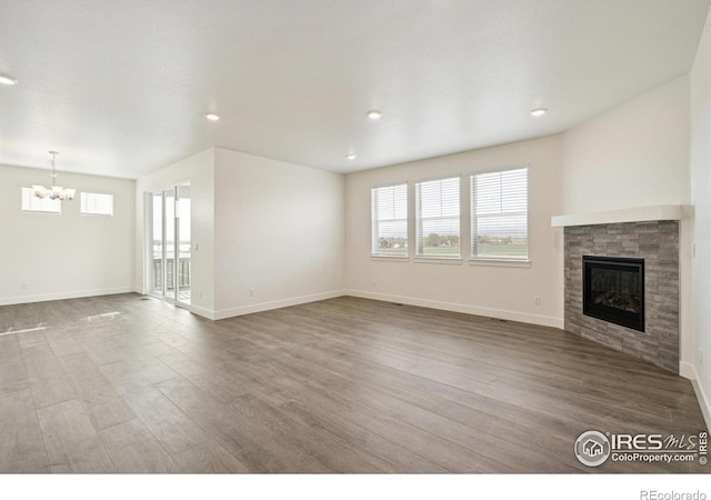 1842 Chaffee Crest Dr, Berthoud, CO 80513 - unfurnished living room featuring a chandelier, a glass covered fireplace, wood finished floors, healthy amount of natural light, and recessed lighting