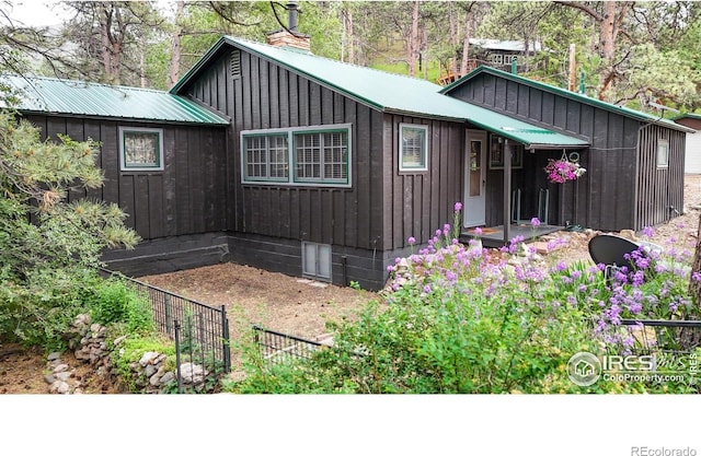 30 Falls Creek Dr, Bellvue, CO 80512 - view of property exterior with board and batten siding, a metal roof, and a chimney