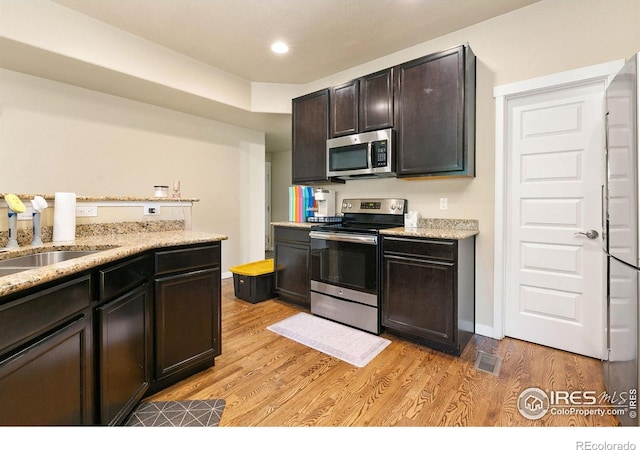 3001 Nebula Ct, Loveland, CO 80537 - kitchen featuring appliances with stainless steel finishes, light wood-type flooring, light stone counters, and recessed lighting