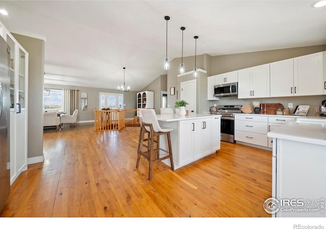 34427 County Rd W, Hillrose, CO 80733 - kitchen featuring stainless steel appliances, vaulted ceiling, a breakfast bar, a kitchen island, and light countertops