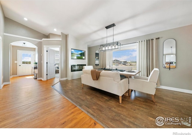 34427 County Rd W, Hillrose, CO 80733 - living area featuring light wood-style flooring, a glass covered fireplace, arched walkways, recessed lighting, and vaulted ceiling