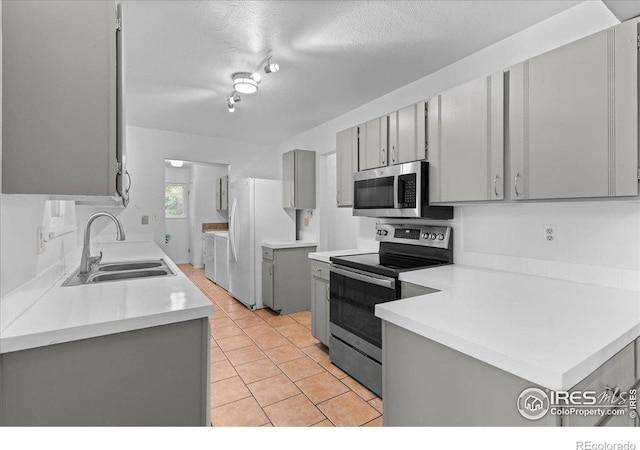 3421 Surrey Ln, Fort Collins, CO 80524 - kitchen featuring gray cabinetry, appliances with stainless steel finishes, washer and dryer, light countertops, and a textured ceiling