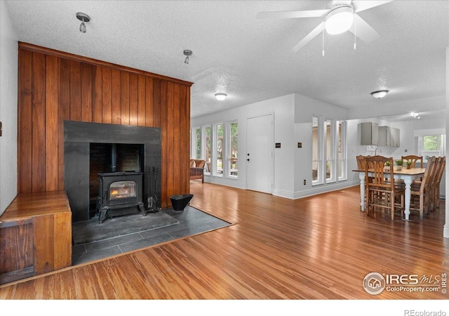 3421 Surrey Ln, Fort Collins, CO 80524 - unfurnished living room with wood finished floors, a wood stove, a textured ceiling, and ceiling fan
