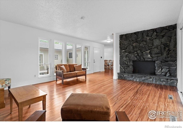 3421 Surrey Ln, Fort Collins, CO 80524 - living area featuring light wood-type flooring, a textured ceiling, and a stone fireplace