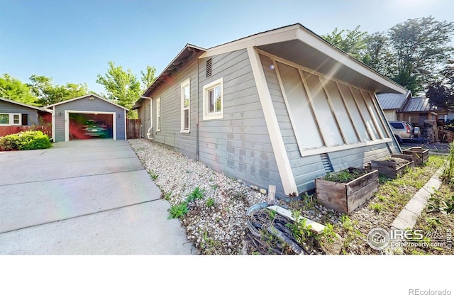 143 W 10th St, Loveland, CO 80537 - view of home's exterior with a garage, concrete driveway, an outbuilding, and a vegetable garden