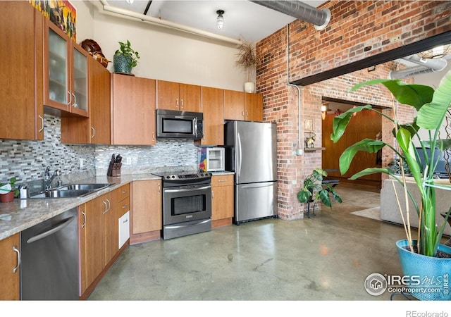 2500 Walnut St Unit 201, Denver, CO 80205 - kitchen with appliances with stainless steel finishes, a high ceiling, finished concrete flooring, brown cabinets, and backsplash