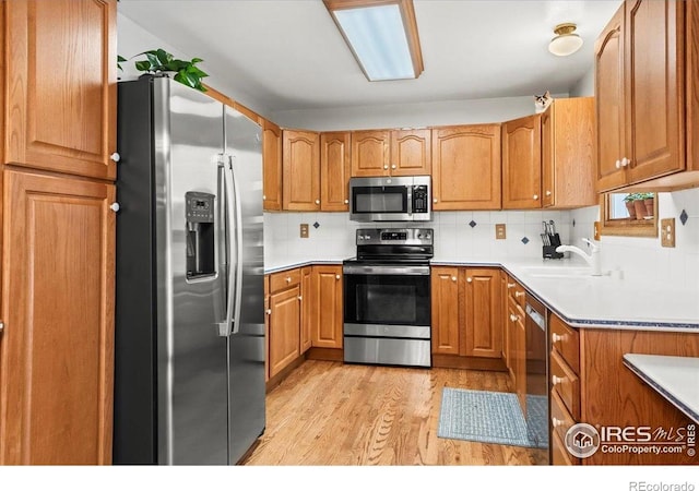 4324 W 22nd St, Greeley, CO 80634 - kitchen with stainless steel appliances, light wood finished floors, decorative backsplash, and brown cabinetry