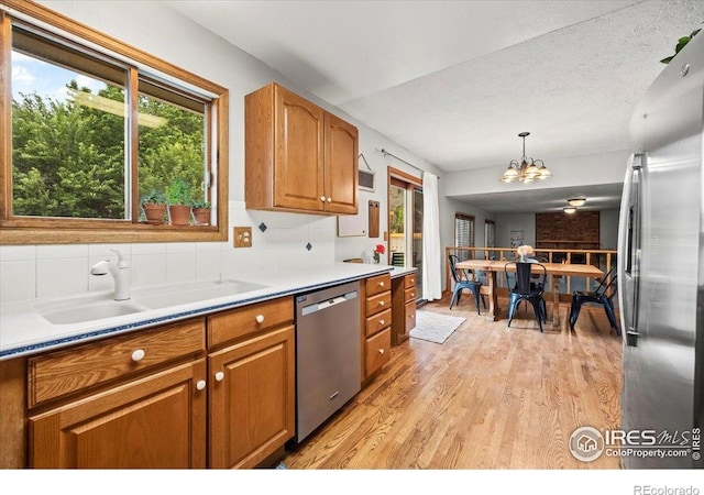 4324 W 22nd St, Greeley, CO 80634 - kitchen featuring appliances with stainless steel finishes, light wood-type flooring, brown cabinets, a chandelier, and pendant lighting