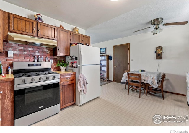 2110 Charro Ave, Longmont, CO 80504 - kitchen with stainless steel gas range, freestanding refrigerator, under cabinet range hood, light countertops, and brown cabinetry