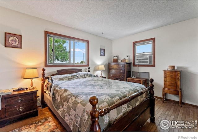 2110 Charro Ave, Longmont, CO 80504 - bedroom featuring multiple windows, wood-type flooring, cooling unit, and a textured ceiling