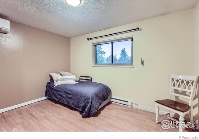 2912 Worthington Ave, Fort Collins, CO 80526 - bedroom featuring wood finished floors, baseboard heating, a textured ceiling, and a wall unit AC