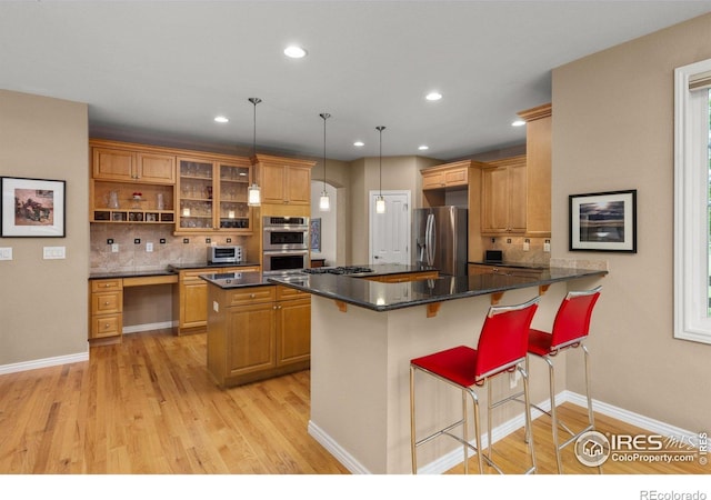 1231 Hawk Ridge Rd, Lafayette, CO 80026 - kitchen with appliances with stainless steel finishes, backsplash, light wood-type flooring, a breakfast bar area, and recessed lighting