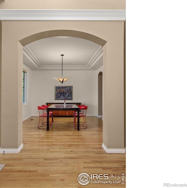 1231 Hawk Ridge Rd, Lafayette, CO 80026 - dining area featuring arched walkways, a tray ceiling, light wood-style floors, and crown molding