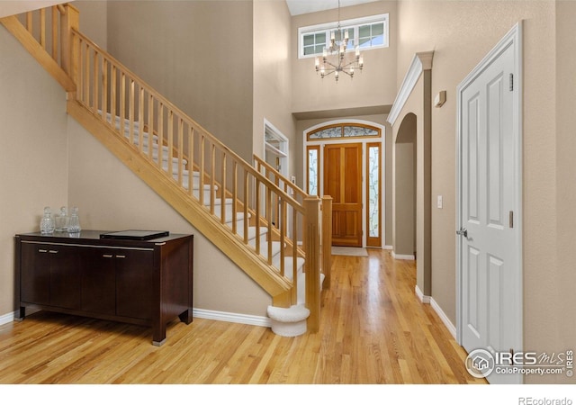 1231 Hawk Ridge Rd, Lafayette, CO 80026 - foyer featuring wood finished floors, stairway, a chandelier, a towering ceiling, and arched walkways