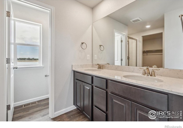 850 Mesic Ln, Windsor, CO 80550 - bathroom featuring double vanity, wood finished floors, and a walk in closet