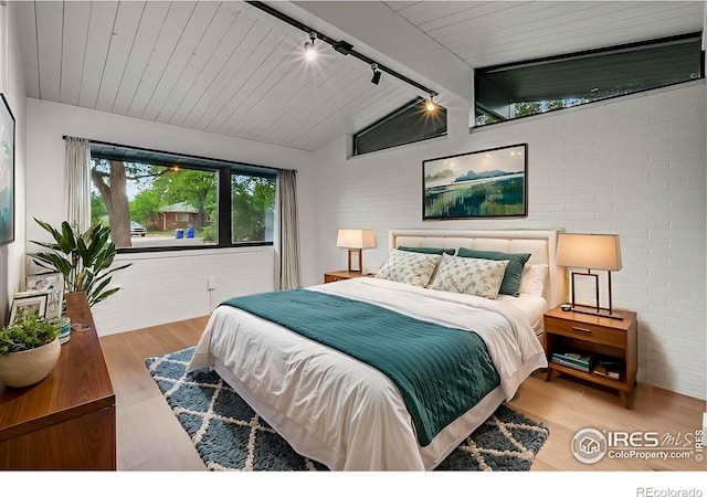 2009 18th Ave, Greeley, CO 80631 - bedroom featuring rail lighting, wood finished floors, and brick wall
