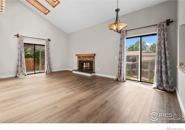 7414 Benton St, Arvada, CO 80003 - unfurnished living room with high vaulted ceiling, wood finished floors, and a glass covered fireplace