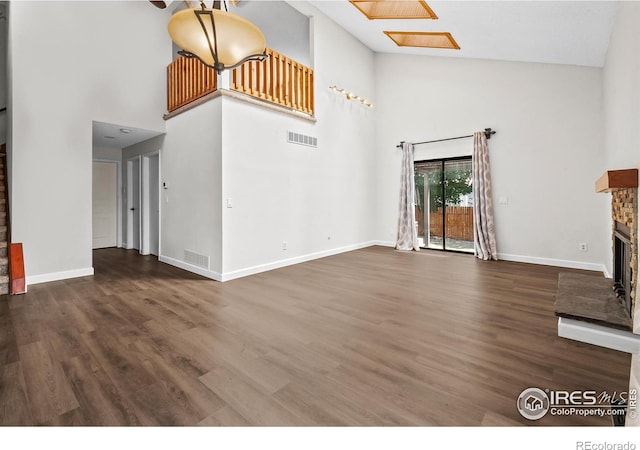 7414 Benton St, Arvada, CO 80003 - unfurnished living room featuring high vaulted ceiling, a fireplace with raised hearth, and wood finished floors