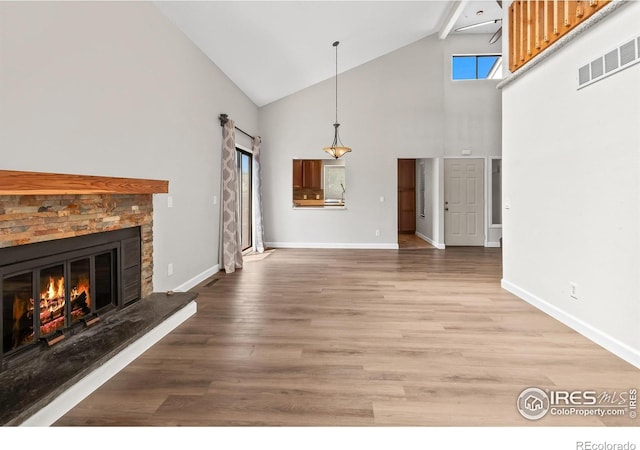 7414 Benton St, Arvada, CO 80003 - unfurnished living room with high vaulted ceiling, a fireplace, and wood finished floors