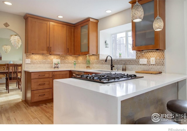 1620 Oak Ave, Boulder, CO 80304 - kitchen featuring brown cabinetry, light wood finished floors, gas cooktop, light countertops, and glass insert cabinets