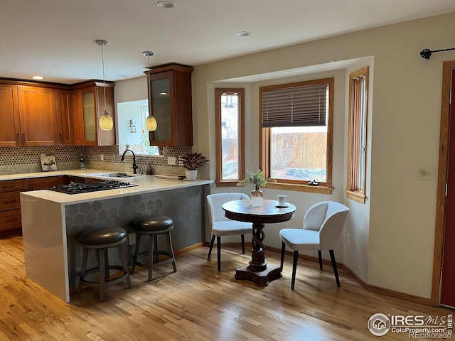 1620 Oak Ave, Boulder, CO 80304 - kitchen with black gas cooktop, light countertops, backsplash, a kitchen breakfast bar, and glass insert cabinets