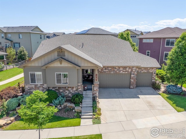 1963 Blue Yonder Way, Fort Collins, CO 80525 - view of front facade with board and batten siding, a garage, driveway, stone siding, and a shingled roof