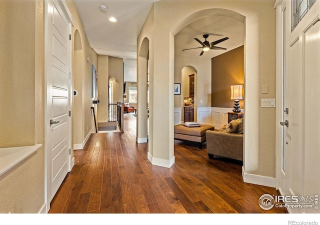 1963 Blue Yonder Way, Fort Collins, CO 80525 - corridor featuring arched walkways, dark wood finished floors, wainscoting, and recessed lighting